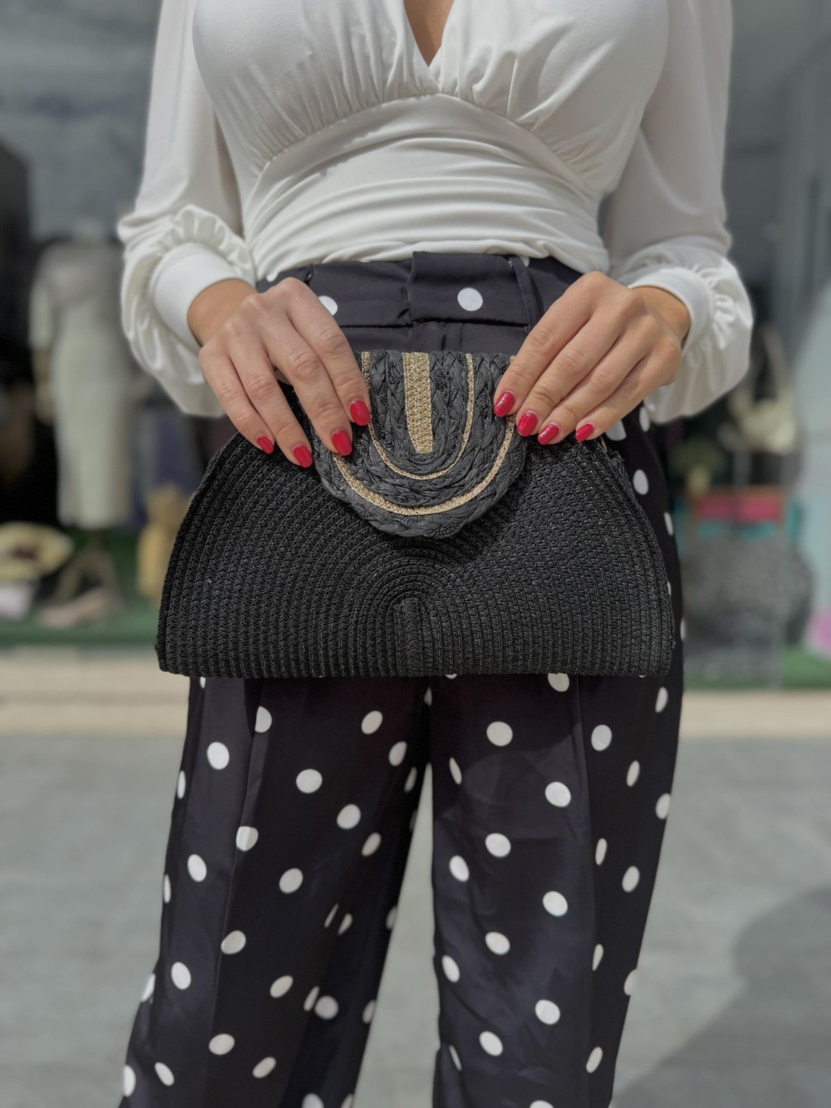 Bolso estilo medialuna de rafia con filos dorados.