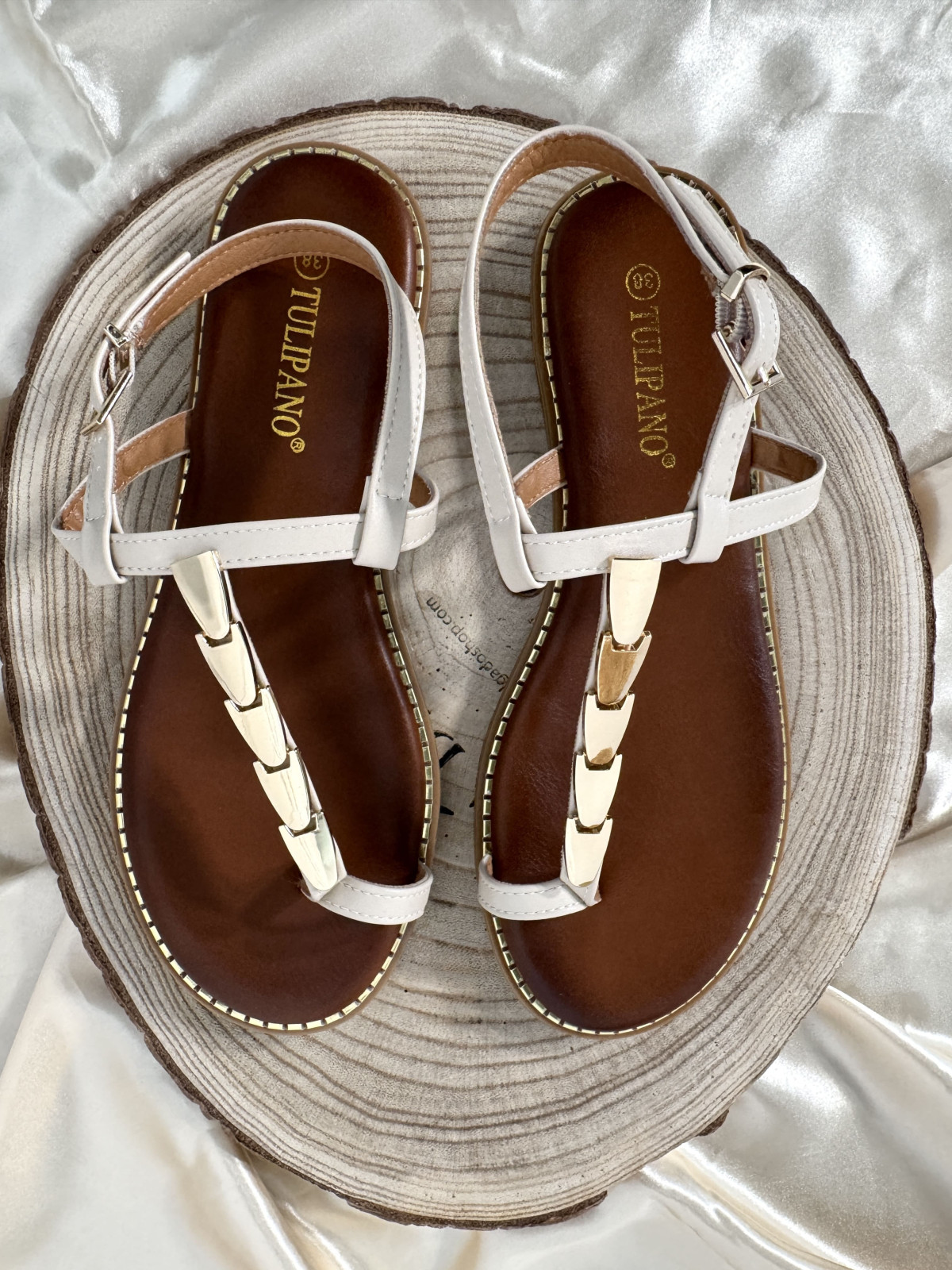 Sandalia de tiras beige, con adorno de chapas metálicas color dorado.