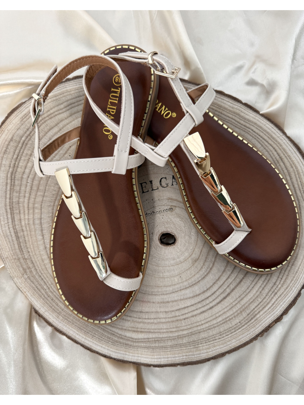 Sandalia de tiras beige, con adorno de chapas metálicas color dorado.