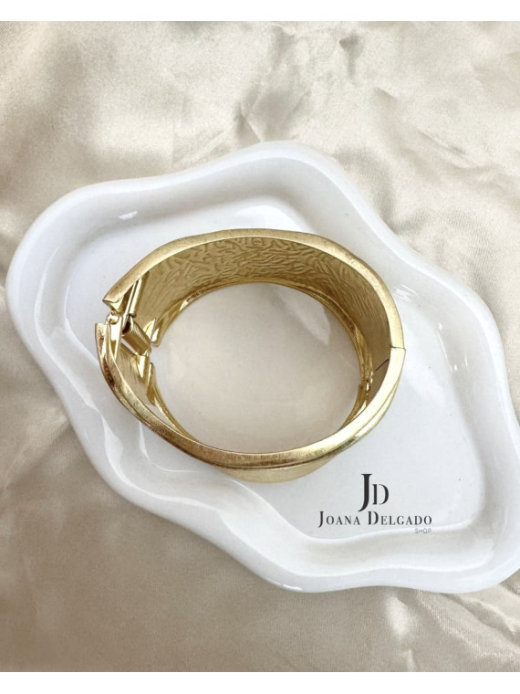 Brazalete metálico dorado con diseño ondulado, ideal para complementar