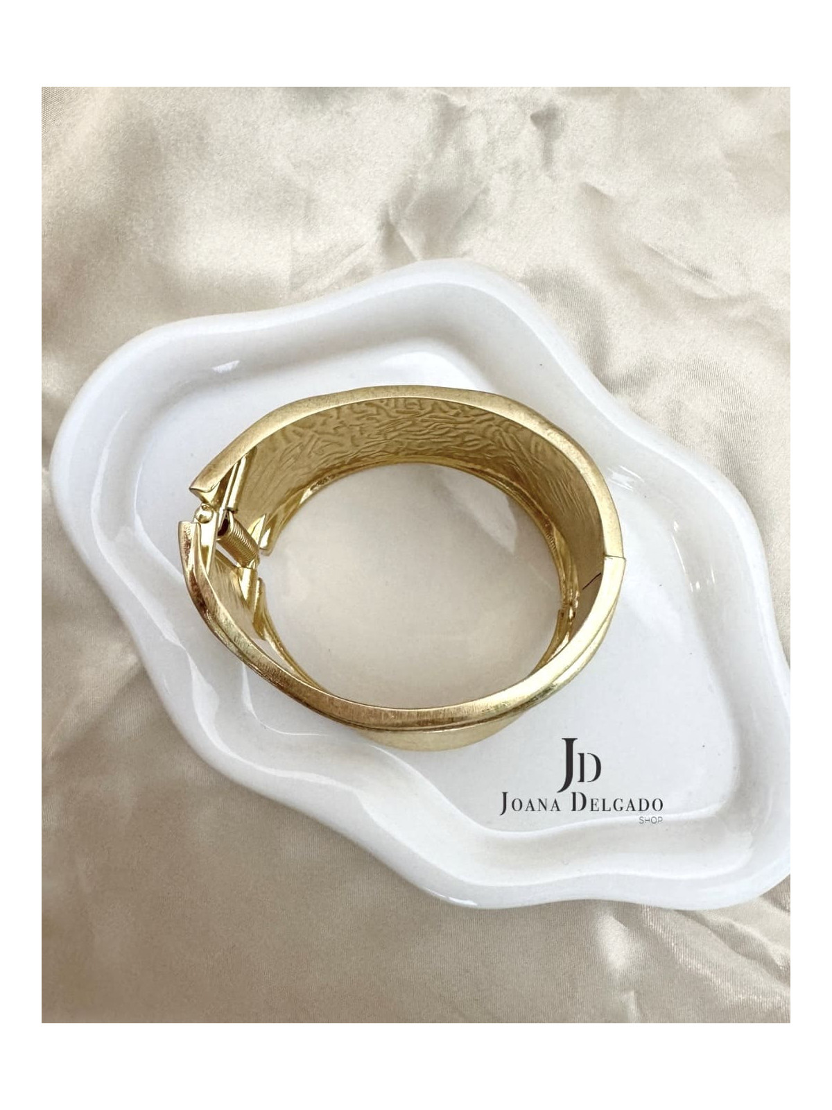 Brazalete metálico dorado con diseño ondulado, ideal para complementar