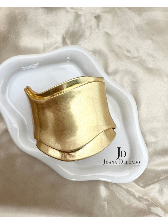 Brazalete metálico dorado con diseño ondulado, ideal para complementar
