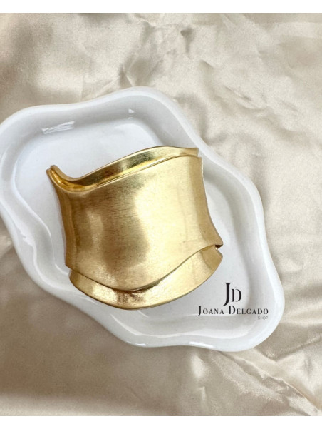 Brazalete metálico dorado con diseño ondulado, ideal para complementar