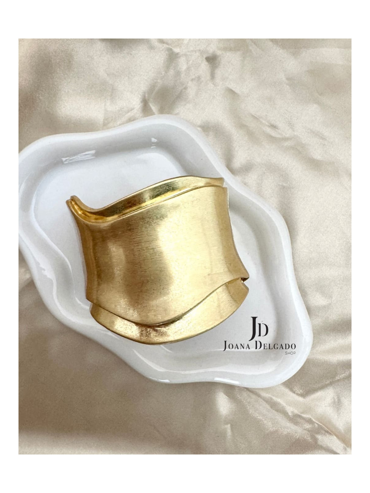 Brazalete metálico dorado con diseño ondulado, ideal para complementar