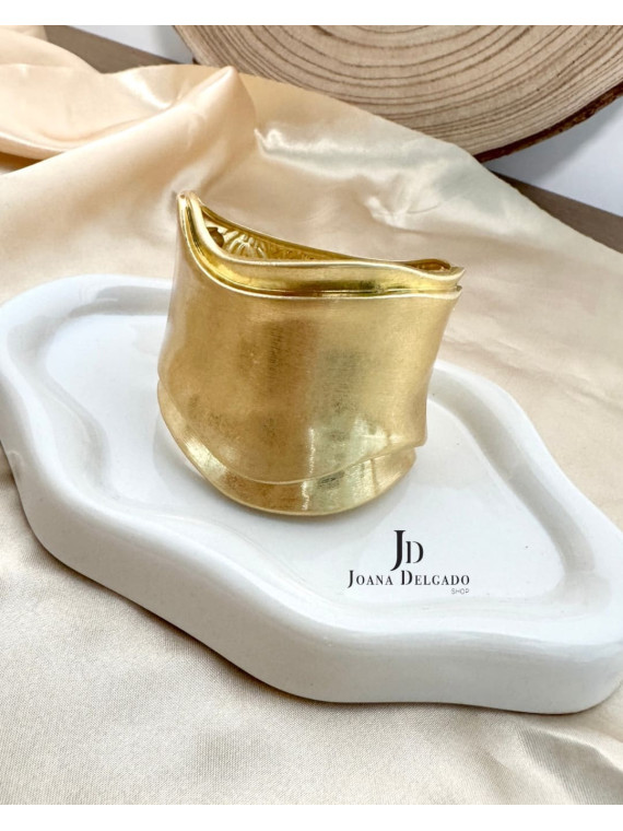 Brazalete metálico dorado con diseño ondulado, ideal para complementar
